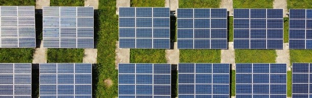 A series of solar panels arranged in rows on a grassy field