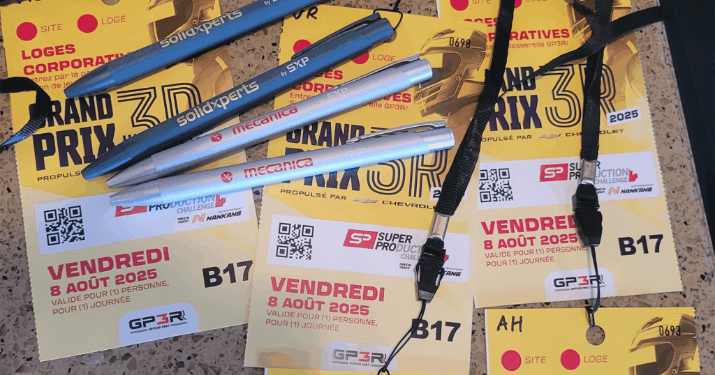 Close-up of several yellow Grand Prix 3R 2025 corporate lounge passes laid out on a countertop, along with black lanyards and branded pens.